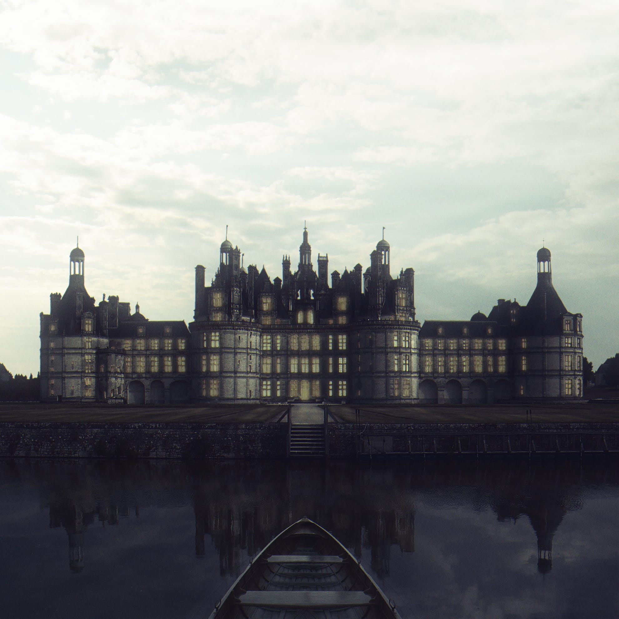 A large, majestic castle with numerous turrets and lit windows is seen at dusk. It stands by a calm body of water, reflecting its silhouette. A small boat is docked at the water's edge, centered in the foreground. The sky is overcast, adding a moody ambiance.