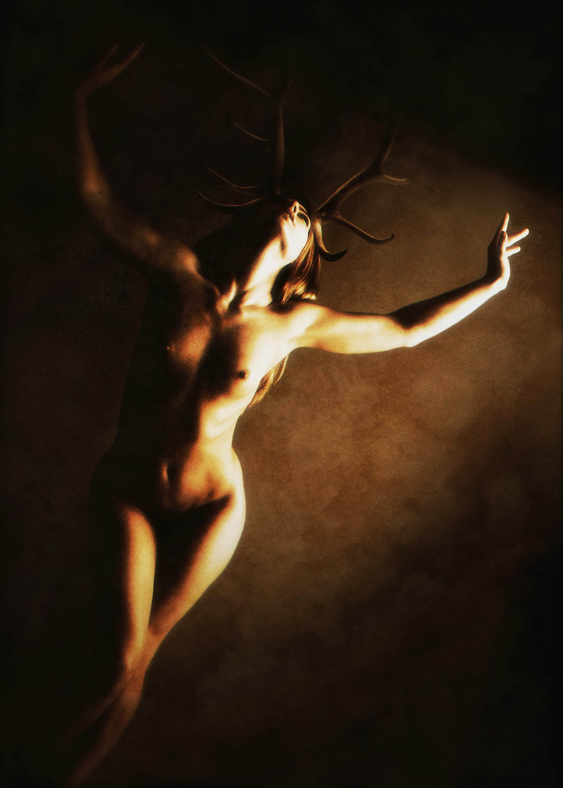 A dimly lit, artistic image depicts a nude individual with long hair and antlers on their head. The figure is extending their arms elegantly, head tilted back, creating a sense of motion and grace. The dusky lighting with deep shadows accentuates the contours of the body, giving a surreal, dreamlike feel.