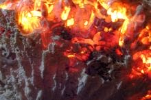 Close-up of vivid orange and yellow molten lava with dynamic, bright streaks and glowing areas. The textured surface appears rough and raw, with darker, shadowed crevices adding depth and contrast to the fiery landscape.
