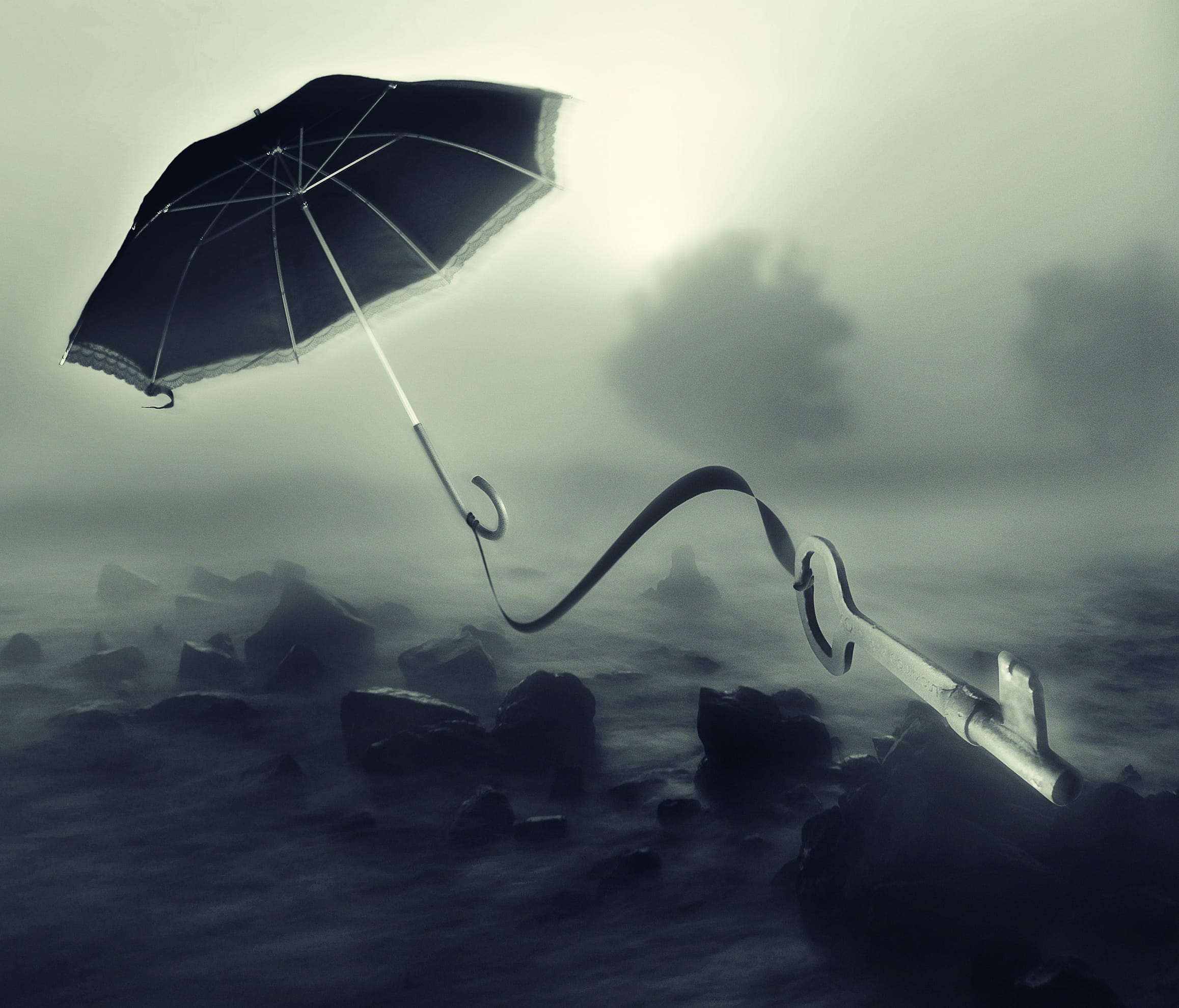 A black umbrella with a curved handle floats in a misty, surreal landscape. The umbrella is tethered by a long ribbon to a metal key partially embedded in rocky, shallow water. The background features blurred, shadowy shapes of trees drifting away, adding to the dreamlike atmosphere.