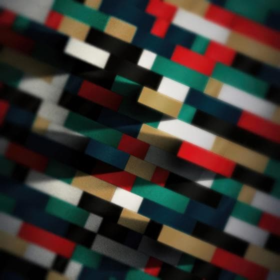 Abstract image featuring a retro pattern of interlocking, multicolored rectangular blocks in red, green, blue, white, black, and beige. The blocks create a layered, three-dimensional effect with varying light and shadow, producing a sense of depth and texture throughout the composition.