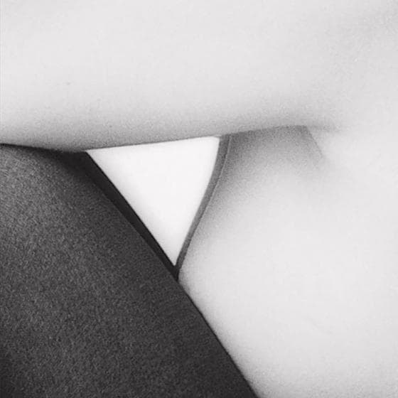 Part of the Presence Series, this black and white abstract image captures the importance of contrast with a close-up view of a bent arm resting over a fabric-covered leg. The positioning creates a striking triangular negative space between them, highlighting the interplay between light skin and dark clothing.