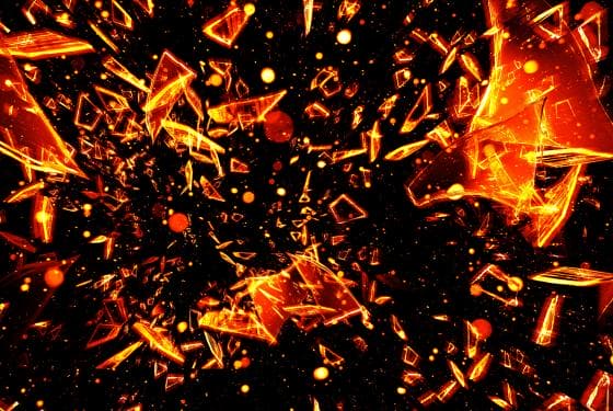 Abstract digital artwork depicting a dynamic explosion of glowing orange shards against a dark background. The shards vary in size and shape, creating a sense of movement and chaos. Small specks and lines surround the fragments, enhancing the fiery and energetic atmosphere.