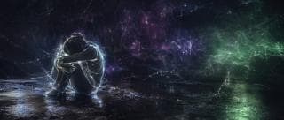 A person sits on the ground hugging their knees, surrounded by glowing colors in a chaotic, dark space.