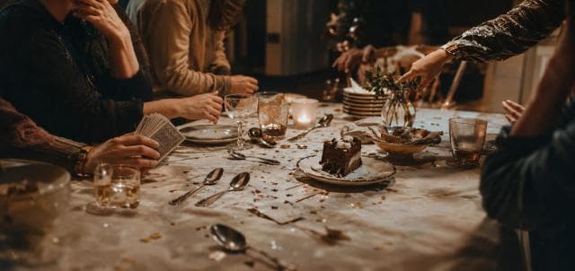 People enjoying dessert, drinks, cards, and confetti together.