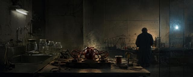 A large artificial heart with wires rests on a table as someone works in the lab behind, symbolizing strength and spirit.