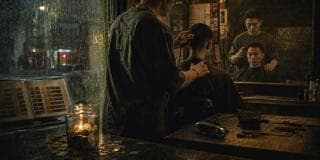 Barber cutting hair at night in a shop; jar of coins and candle by a rainy window, representing strength and spirit.
