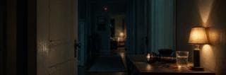 A hallway with a table holding a lamp, keys, water, and flashlight; several rooms are visible in the background.