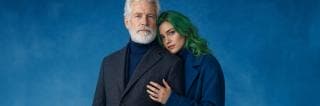 An older man and a green-haired woman in dark coats stand together, conveying a sense of darkness and chaos.