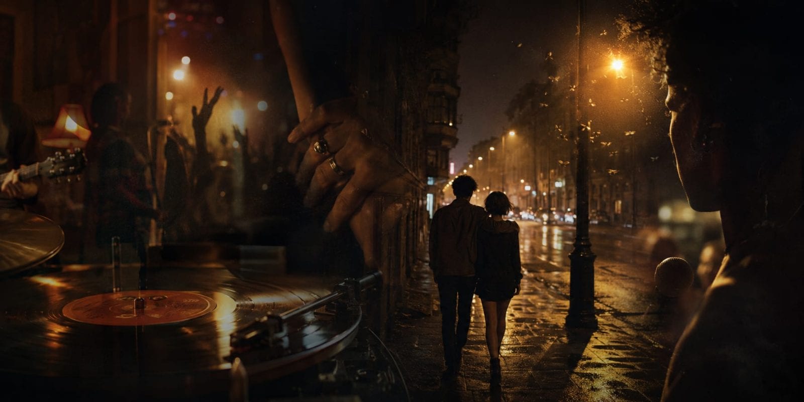 A vinyl record spins, people dance, and a couple walks energetically on a wet city street under streetlights.