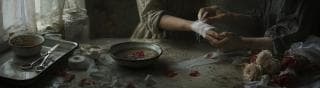 A person wraps another’s bandaged wrist at a table with medical supplies, flowers, and a bowl of water with petals.